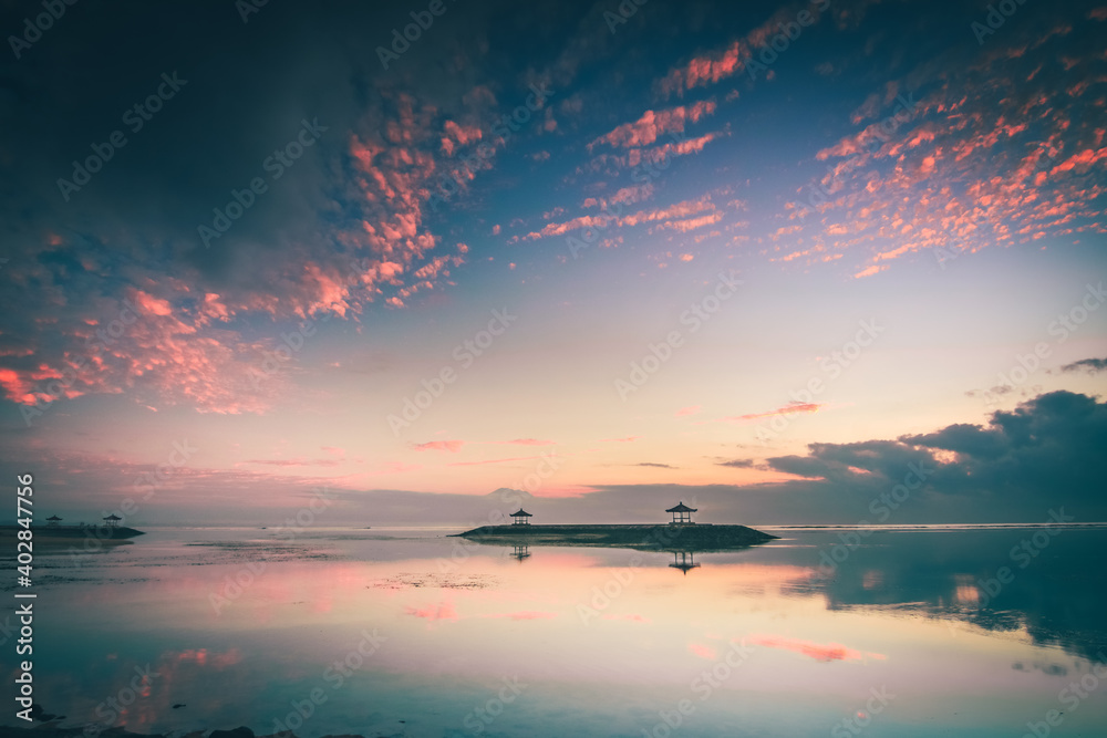 Beautiful sunrise on Bali in Sanur by the sea with a view over the beach to the sea. a temple and breakwater in the sea at sunrise. Hinuistic Beautiful sunrise on Bali in Sanur by the sea with a view over the beach to the sea. a temple and breakwater in the sea at sunrise. Hinuistic