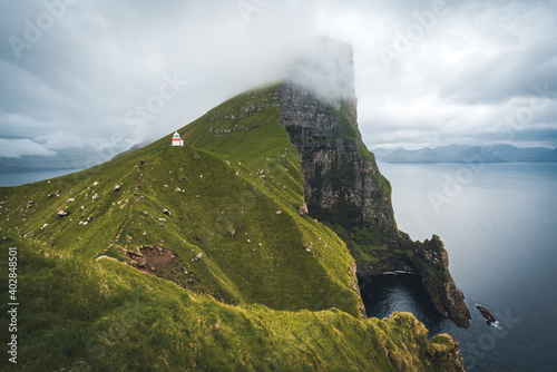 Kalsoy Island with Kallur lighthouse on on Faroe islands, Denmark, Europe. Clouds over high cliffs, turquoise Atlantic ocean and spectacular views.