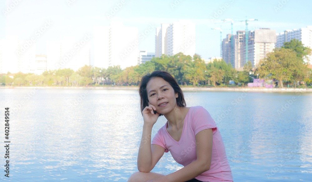 Fototapeta premium A good-looking Asian middle-aged woman with short black hair happily smiles at the camera. Healthy and beautiful woman getting ready to exercise in the morning Where the morning sun shines down