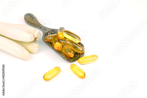 lemongrass capsule essential oil  on wooden spoon with fresh lemongrass on white background