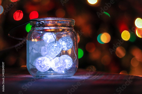 Transparent jar with led lights inside and Bokeh lights in background. Home decoration