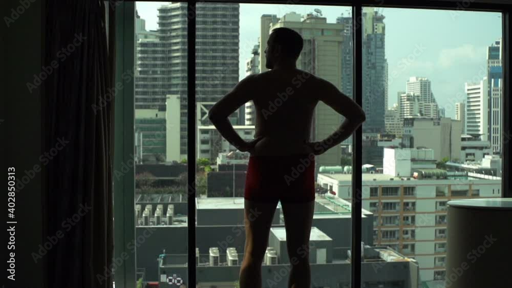 Young man in underwear admire view from window at home, slow motion Young man in underwear admire view from window at home, slow motion