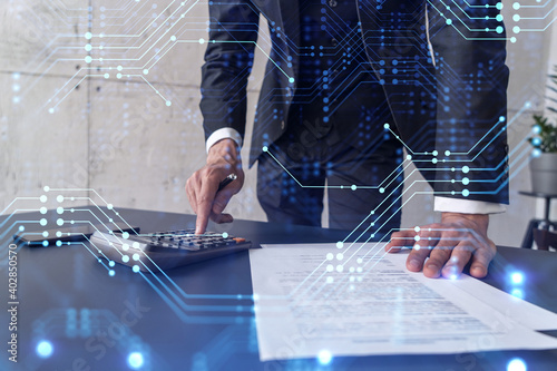 A research and development specialist computing the data to create a new approach to develop high tech business. Technological icons over the desk with calculator. photo