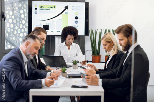 Business, company strategy, financial report concept. Team of diverse multiethnic businesspeople working with financial reports and company sales charts, having a meeting at office