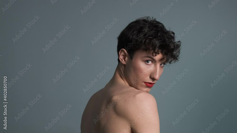 Portrait of a transgender with makeup posing on grey background. Close-up. Masculine and feminine characteristics in one person. Gender identity concept 4k Portrait of a transgender with makeup posing on grey background. Close-up. Masculine and feminine characteristics in one person. Gender identity concept 4k