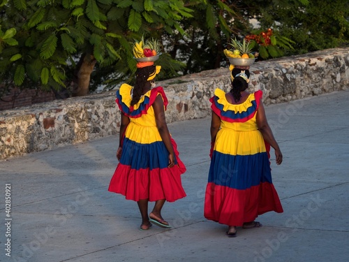 Afrocolombian women fruit vendor seller in colombian colored dress skirt costume walking in Cartagena de Indias Colombia photo