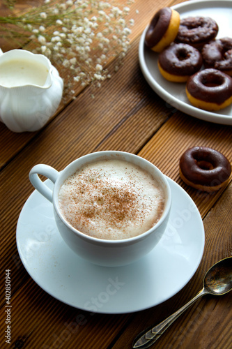 Cup of coffee,milk saucer and donuts, on wooden table with copy space.