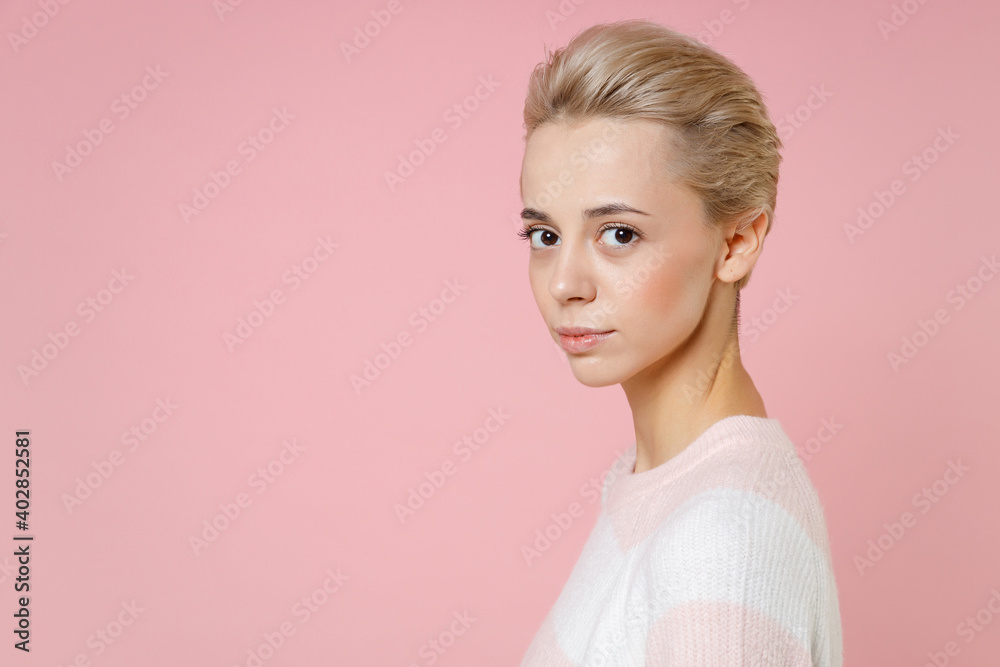 Side view of young nice attractive caucasian blonde beautiful woman 20s short haircut nude makeup in casual knitted sweater looking camera isolated on pastel pink background studio close up portrait. Side view of young nice attractive caucasian blonde beautiful woman 20s short haircut nude makeup in casual knitted sweater looking camera isolated on pastel pink background studio close up portrait.