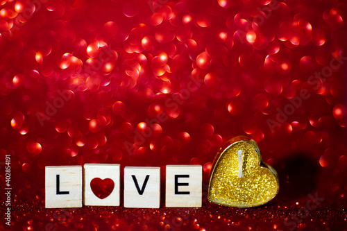 Word love in wooden letters on a bright red shiny background. Happy Valentine's Day, Mother's Day, March 8, World Women's Day holiday card concept. candle heart with glitter