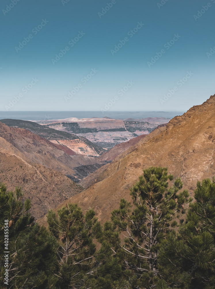 Scenic view of the high atlas mountains directly after sunrise. Wide angle view towards canyon. Berber village in foreground. Trail coming back from the summit of Mount Toubkal, Atlas, Morocco. The Scenic view of the high atlas mountains directly after sunrise. Wide angle view towards canyon. Berber village in foreground. Trail coming back from the summit of Mount Toubkal, Atlas, Morocco. The