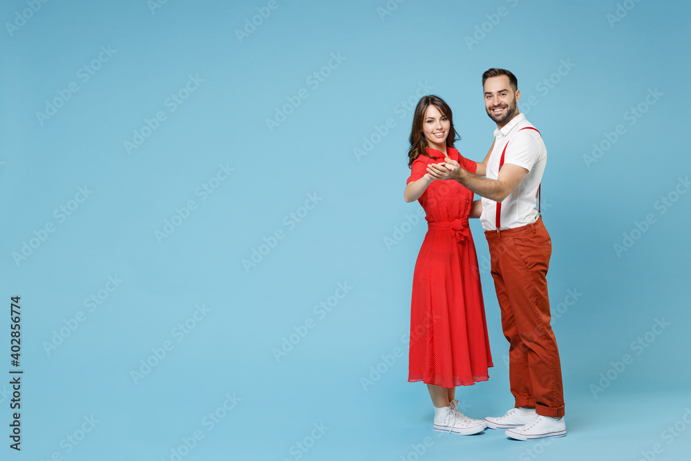 Full length of beautiful funny young couple two friends man woman in white red clothes dancing having fun isolated on pastel blue color background studio portrait. St. Valentine's Day holiday concept.