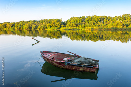 Fototapeta Naklejka Na Ścianę i Meble -  A wooden boat in the river, fishing boat in a calm lake water/old wooden fishing boat, wooden fishing boat in a still lake water