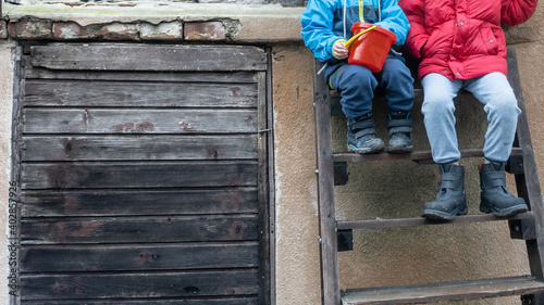 Children sitting on old staircase outside in winter