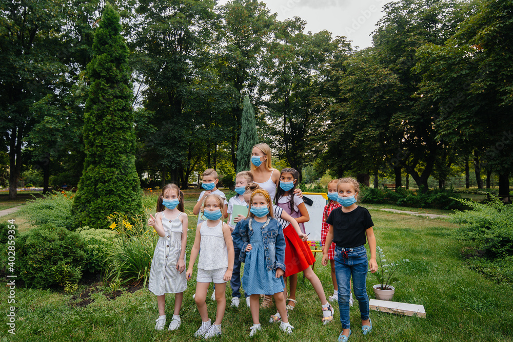 Obraz premium A class of masked school children is engaged in outdoor training during the epidemic. Back to school, learning during the pandemic