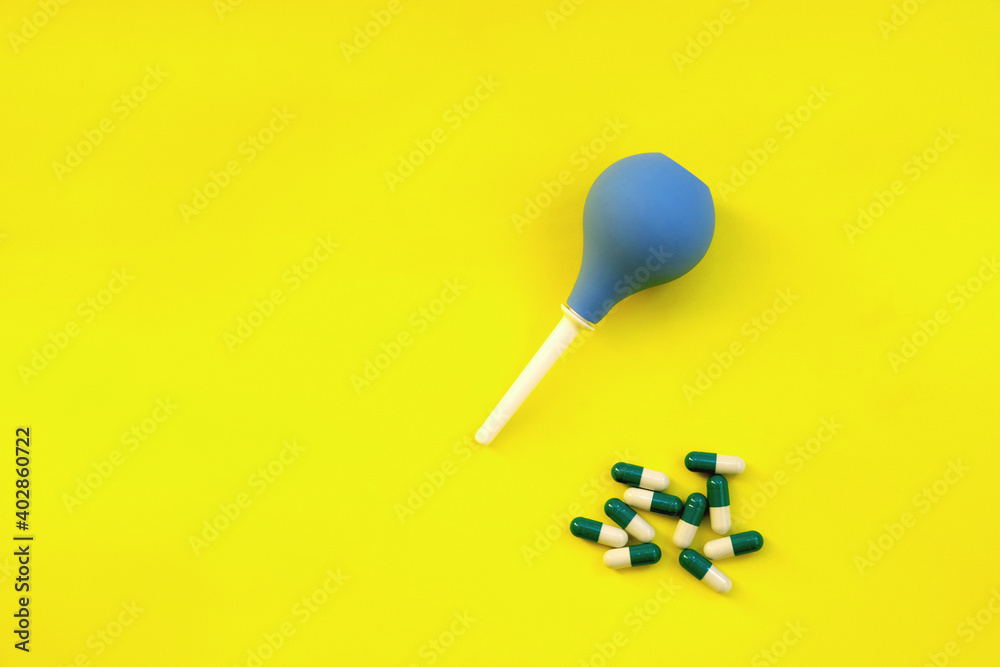 Enema and pills on a yellow background, flat lay. Place for text.
Enema and pills on a yellow background, flat lay. Place for text.