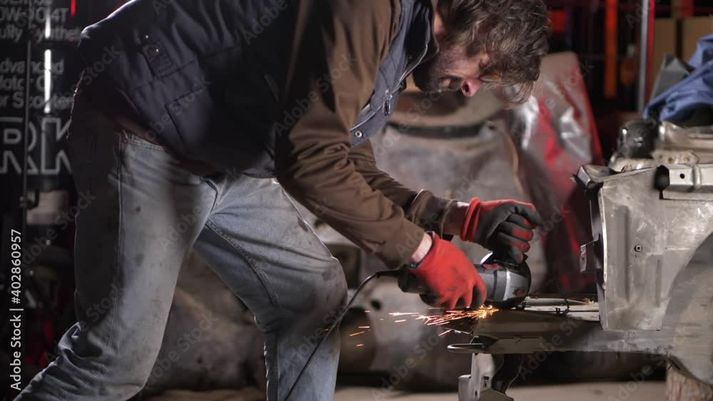 Slow motion fiery sparks guy in garage cutting vehicle metal parts in workshop