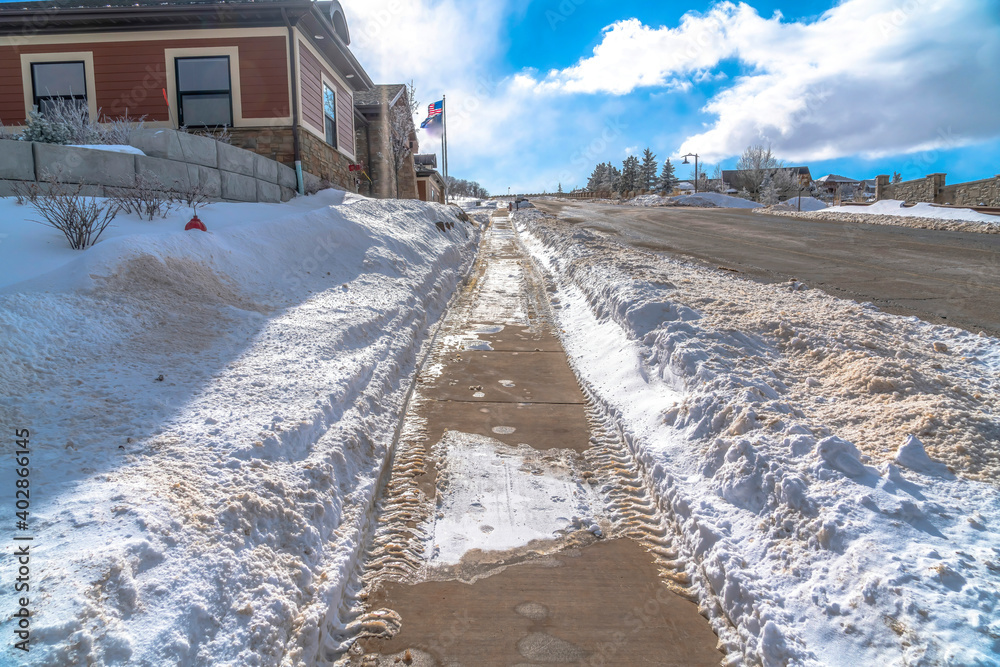 Pathway with tire tracks along road on snowy neighborhood on a sunny winter day