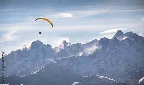 Photos Parasailor glides over snowcapped mountains and lofty clouds