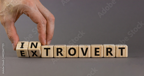 Introvert or extrovert symbol. Hand turns cubes and changes the word 'introvert' to 'extrovert'. Beautiful grey background, copy space. Psychological and Introvert or extrovert concept. photo