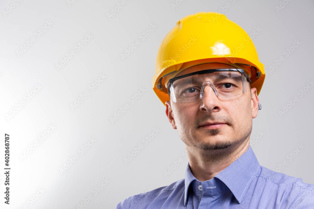 Engineer with yellow helmet and jeans shirt near a industrial wall, inspiring confidence. Engineer with yellow helmet and jeans shirt near a industrial wall, inspiring confidence.