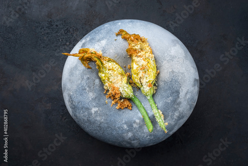 Modern style traditional fried fiori di zucchini fritti with crumbles served as top view on a design plate with copy space photo