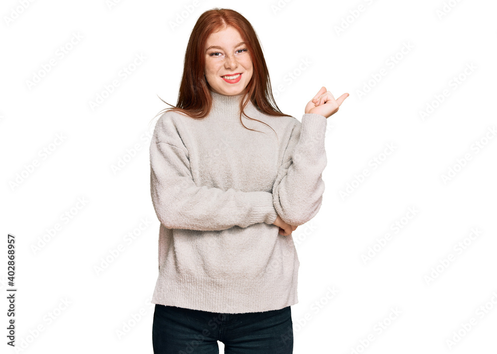 Young read head woman wearing casual winter sweater smiling happy pointing with hand and finger to the side Young read head woman wearing casual winter sweater smiling happy pointing with hand and finger to the side