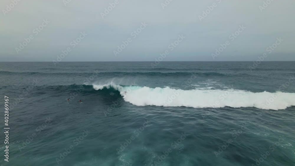 High angle aerial view of surfers riding ocean wave High angle aerial view of surfers riding ocean wave
