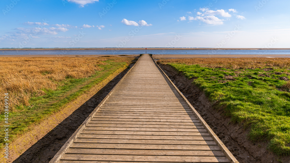 A wooden path leading to the shore of the River Ribble, seen in Lytham, Lancashire, England, UK