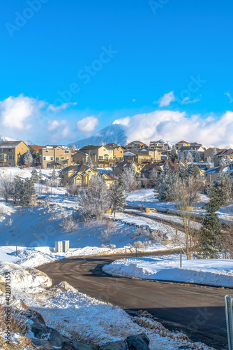 Scenic mountain town with winding road along houses against blue sky and clouds
