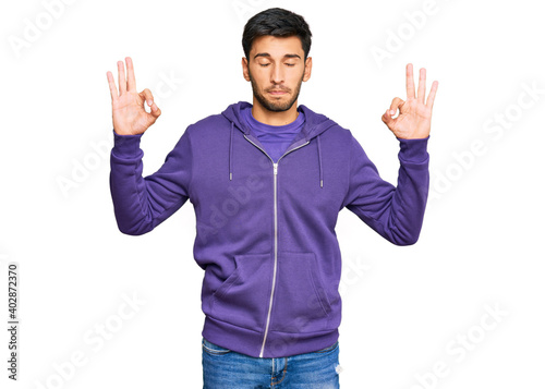 Young handsome man wearing casual sweatshirt relax and smiling with eyes closed doing meditation gesture with fingers. yoga concept. © Krakenimages.com