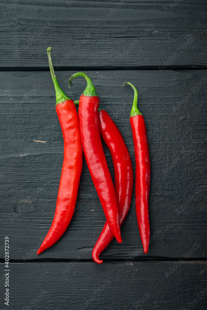Whole red chili peppers, on black wooden background, top view or flat lay