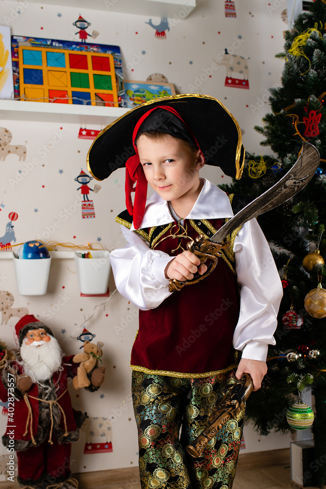 Obraz premium Little boy child dressed as pirate for Halloween on background of Christmas tree. Kid in carnival costumes for Christmas