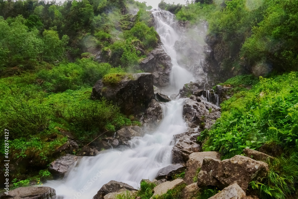 rushing large waterfall with huge rocks in the mountains rushing large waterfall with huge rocks in the mountains