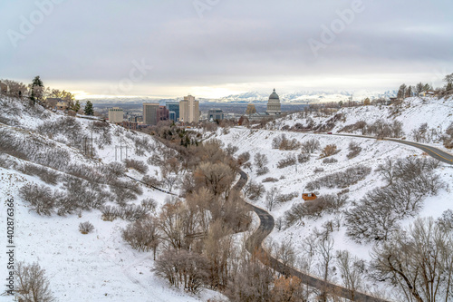 Fototapeta Naklejka Na Ścianę i Meble -  Highway on snowy mountain over Salt Lake City downtown view against cloudy sky