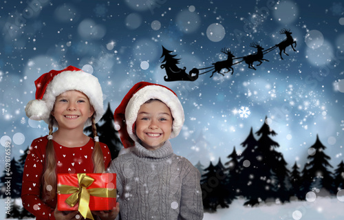 Cute little children and Santa Claus flying in his sleigh against moon sky on background. Christmas celebration