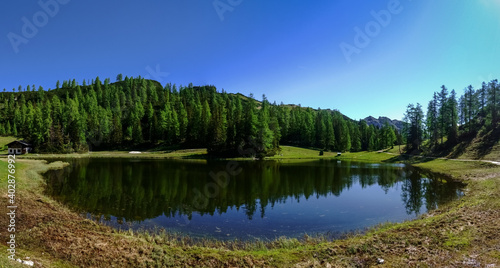 blue sky trees and mountains with a reflection in a lake panorama