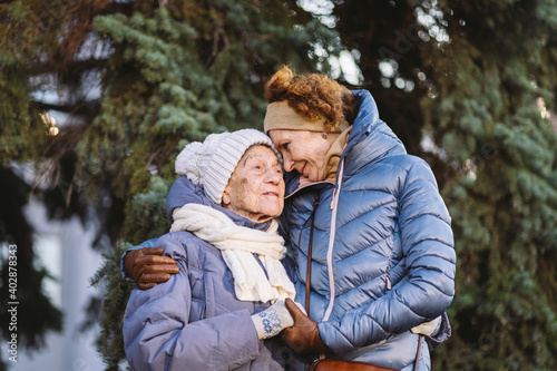 Obraz na plátně Caucasian women senior mother and mature daughter in winter garden on background