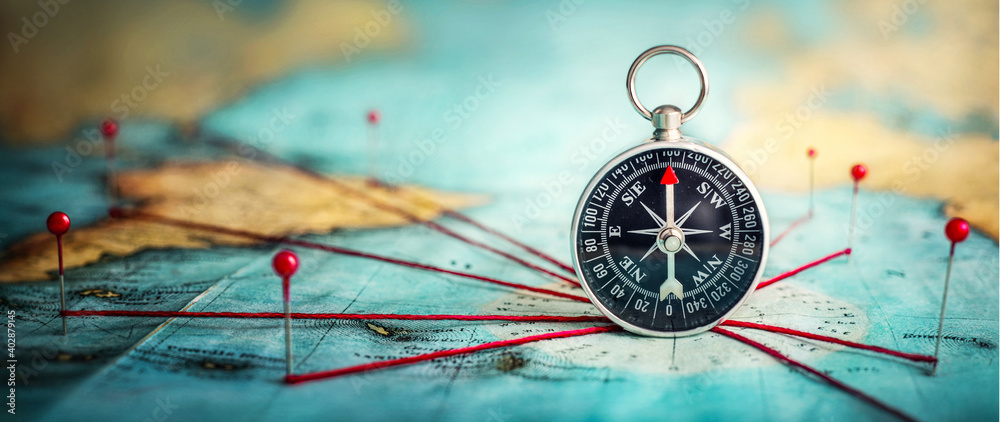 Magnetic compass  and location marking with a pin on routes on world map. Adventure, discovery, navigation, communication, logistics, geography and travel theme concept background.. Macro photo.  - obrazy, fototapety, plakaty 