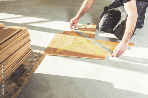 worker installing oak herringbone parquet floor during home improvement