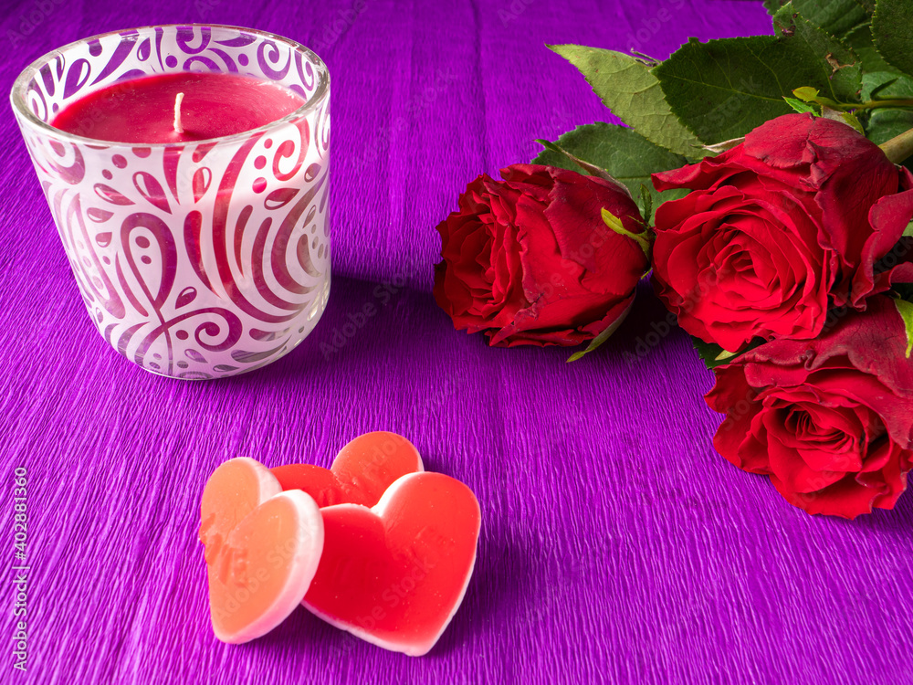red roses next to red candle and red hearts on background red roses next to red candle and red hearts on background