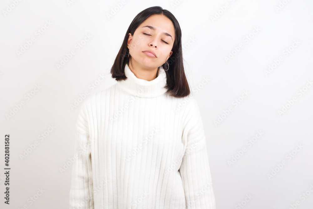 Young brunette woman wearing white knitted sweater against white background looking sleepy and tired, exhausted for fatigue and hangover, lazy eyes in the morning. Young brunette woman wearing white knitted sweater against white background looking sleepy and tired, exhausted for fatigue and hangover, lazy eyes in the morning.
