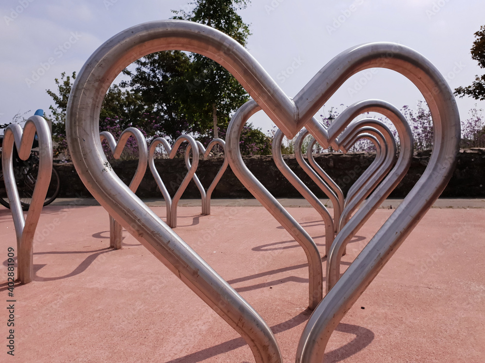 A close up view of the heart shaped bicycle parking racks, located in Greystones town, Ireland. Creative design of a bicycle parking station. Symbol of love for cycling. Sunny summer day.
