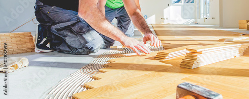 worker installing oak herringbone parquet floor during home improvement photo