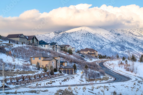 Homes and road on a mountain town overlooking snowy peaks and cloudy sky