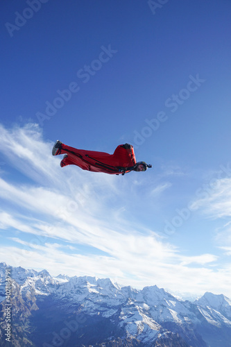 Wingsuit flier glides over snowcapped mountains