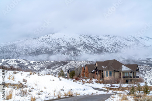 Homes blending with the snow covered terrain against Wasatch Mountain in winter © Jason