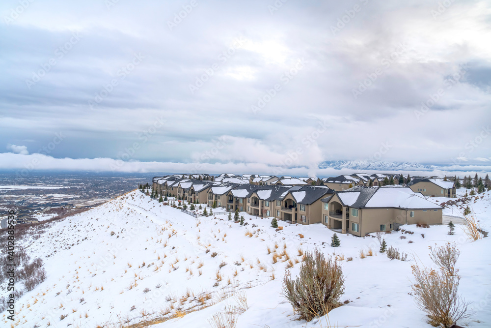 Identical homes on a mountain with view of sweeping valley and vast cloudy sky