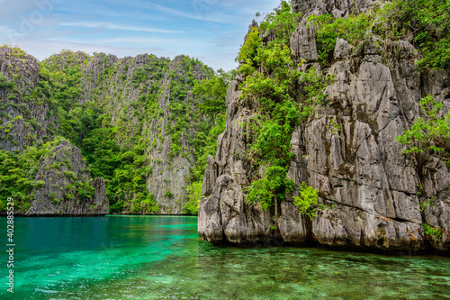 Blue crystal water in paradise Bay with boats on the wooden pier at Kayangan Lake in Coron island, tropical travel destination - Palawan, Philippines.
