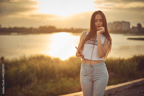 Young beautiful caucasian girl listening to music with smartphone walking in the city with headphones smiling - relax, youth, emancipation concept