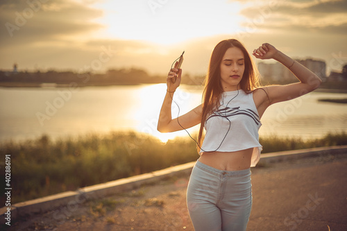 girl listening to music with smartphone walking in the city with headphones smiling - relax, youth, emancipation concept photo